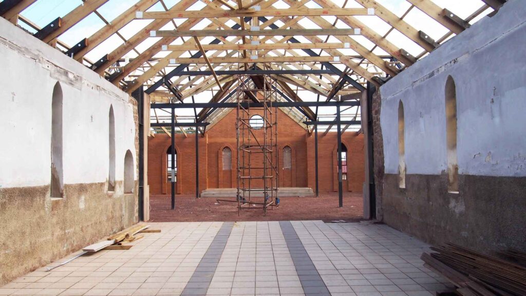 Interior looking down the nave towards the new sanctuary during construction, showing exposed trusses, no roof.  